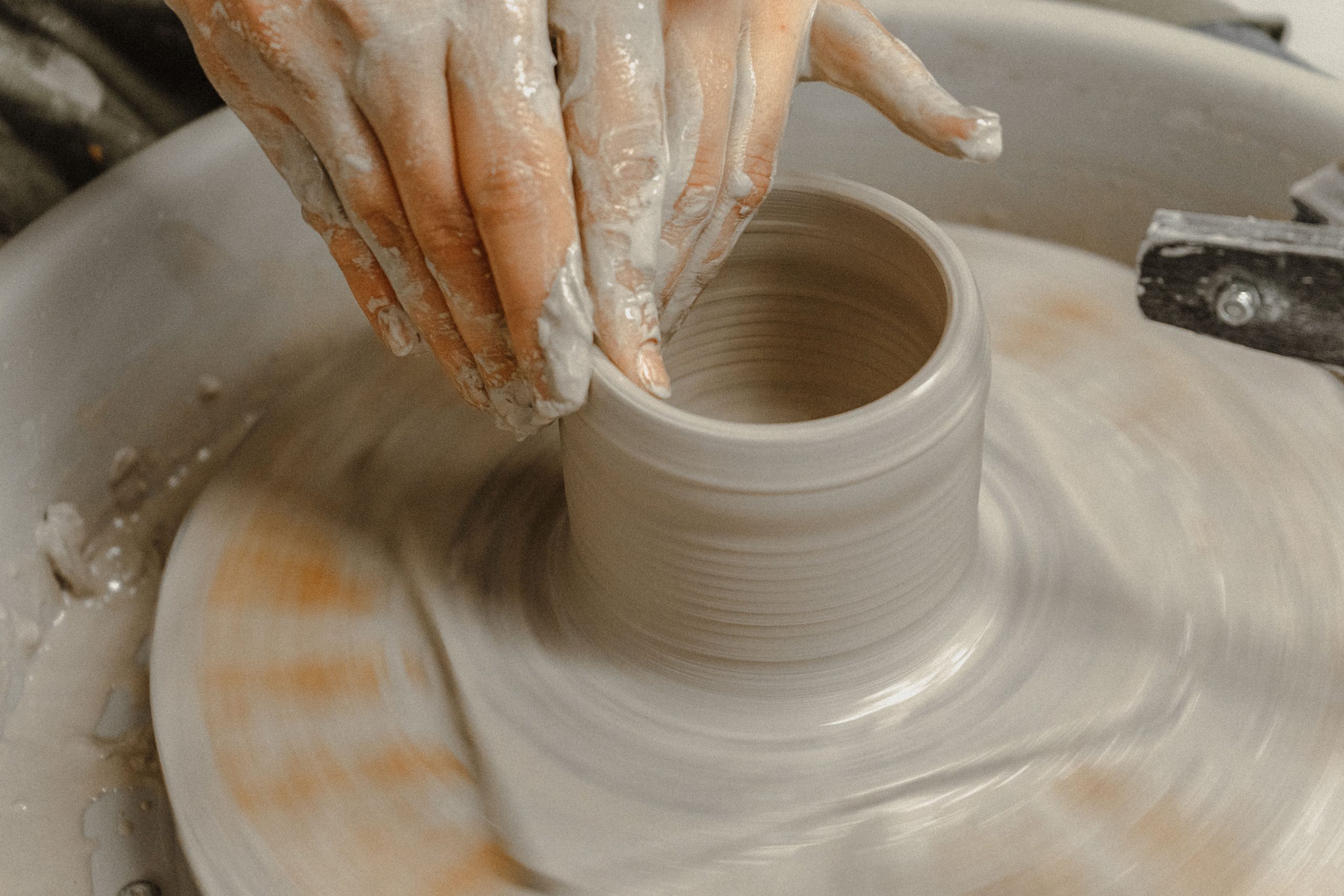 Close-up of hands shaping a clay pot on a pottery wheel, showcasing artisanal craftsmanship.